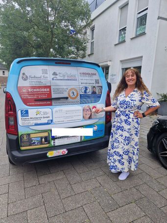 Eine Frau im Kleid steht hinter dem Wagen.