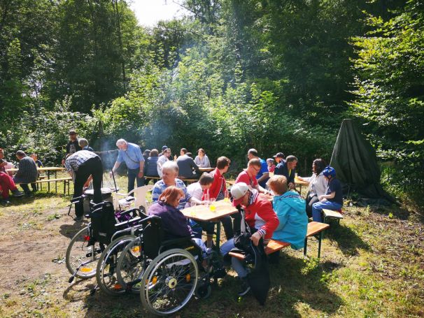 Man sieht ein Bild vom Grill-Fest mit vielen Menschen an einem Tisch.