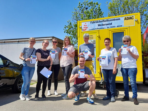 Acht Personen haben eine Urkunde in der Hand und lächeln