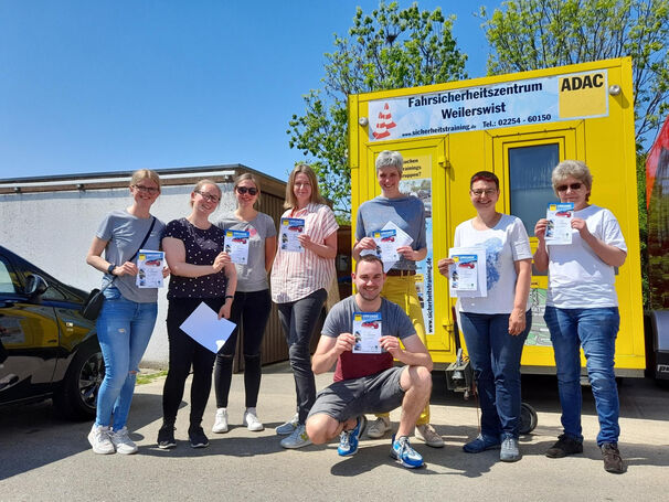 Acht Personen haben eine Urkunde in der Hand und lächeln